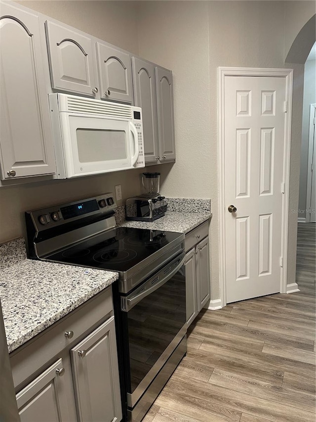 2817 Almaton Loop Unit 403, Kissimmee, FL 34747 - kitchen featuring electric stove, white microwave, light wood-style floors, and gray cabinetry