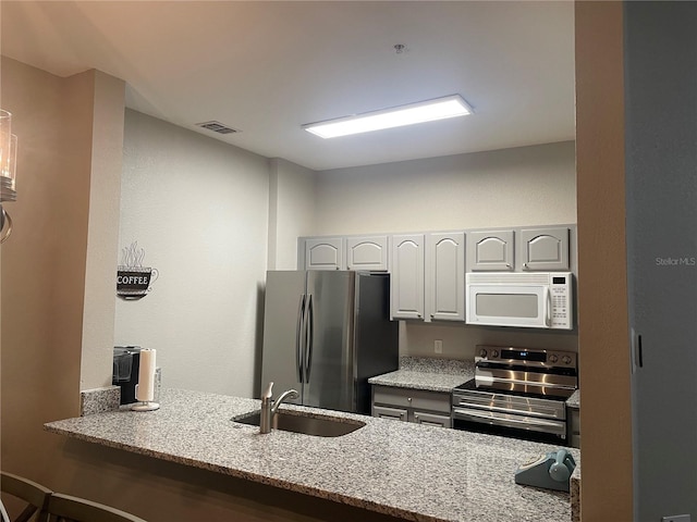 2817 Almaton Loop Unit 403, Kissimmee, FL 34747 - kitchen featuring appliances with stainless steel finishes, light stone counters, a peninsula, and a kitchen bar