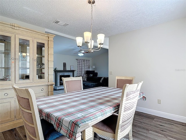 745 Mentmore Cir, Deltona, FL 32738 - dining room featuring a chandelier, dark wood-style floors, a textured ceiling, and a fireplace with raised hearth