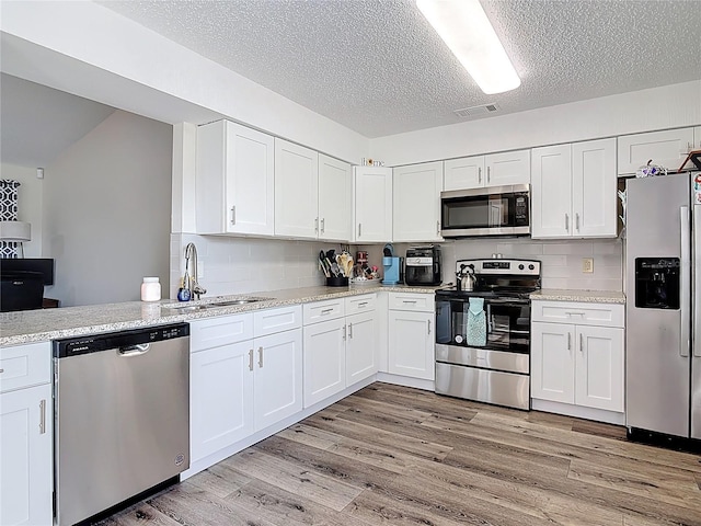 745 Mentmore Cir, Deltona, FL 32738 - kitchen featuring appliances with stainless steel finishes, a textured ceiling, white cabinetry, light wood-style floors, and backsplash