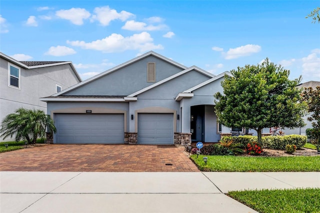 4920 Blanche Ct, Saint Cloud, FL 34772 - view of front of home with decorative driveway, stucco siding, an attached garage, and stone siding