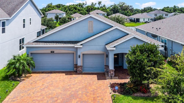 4920 Blanche Ct, Saint Cloud, FL 34772 - view of front of home with stucco siding, a garage, decorative driveway, stone siding, and a residential view
