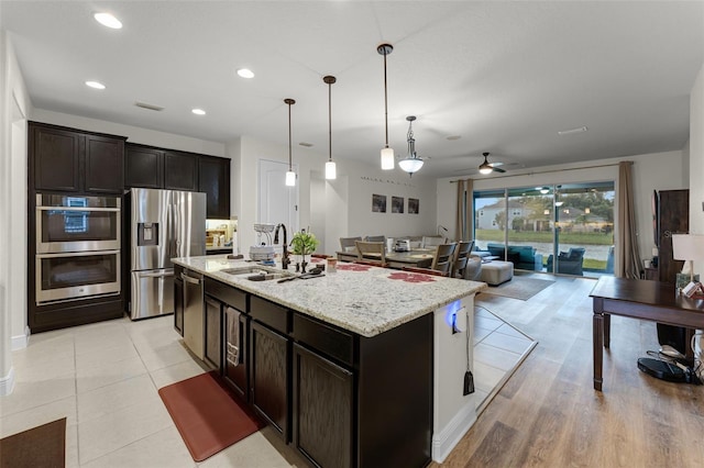 4920 Blanche Ct, Saint Cloud, FL 34772 - kitchen with appliances with stainless steel finishes, a ceiling fan, open floor plan, light stone counters, and hanging light fixtures