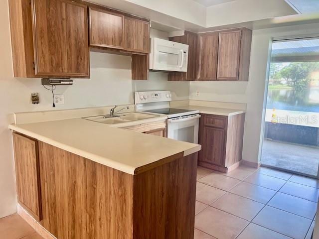 19 W Country Cove Way, Kissimmee, FL 34743 - kitchen with white appliances, light countertops, a peninsula, light tile patterned floors, and brown cabinets