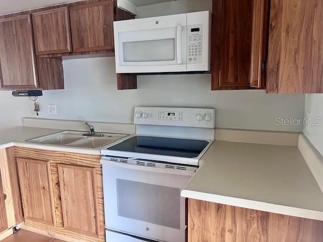 19 W Country Cove Way, Kissimmee, FL 34743 - kitchen with white appliances, light countertops, and brown cabinets