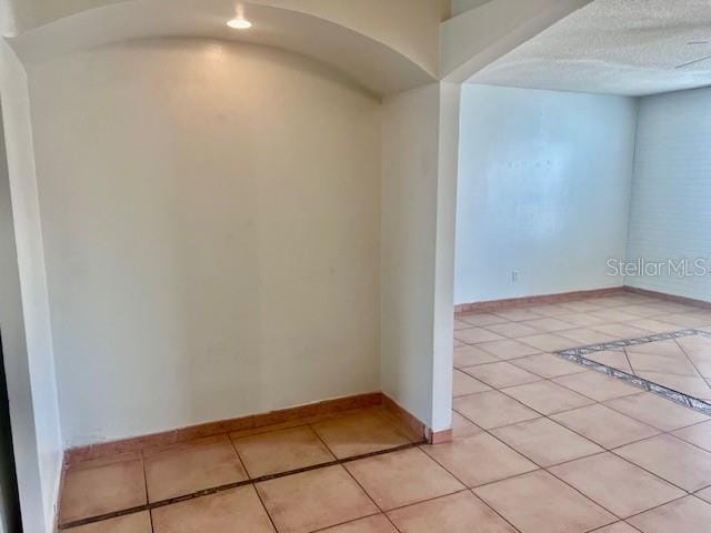 19 W Country Cove Way, Kissimmee, FL 34743 - unfurnished room featuring light tile patterned floors, arched walkways, and a textured ceiling