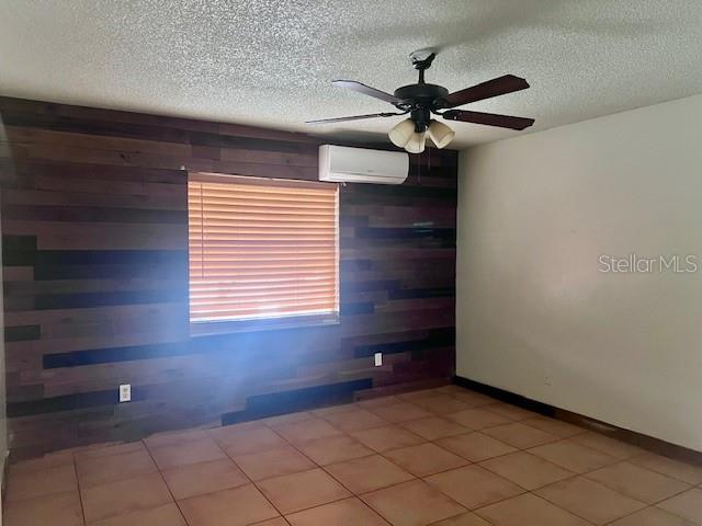 19 W Country Cove Way, Kissimmee, FL 34743 - spare room with a wall unit AC, wood walls, a textured ceiling, and ceiling fan