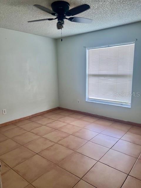 19 W Country Cove Way, Kissimmee, FL 34743 - empty room featuring a ceiling fan, a textured ceiling, and light tile patterned flooring