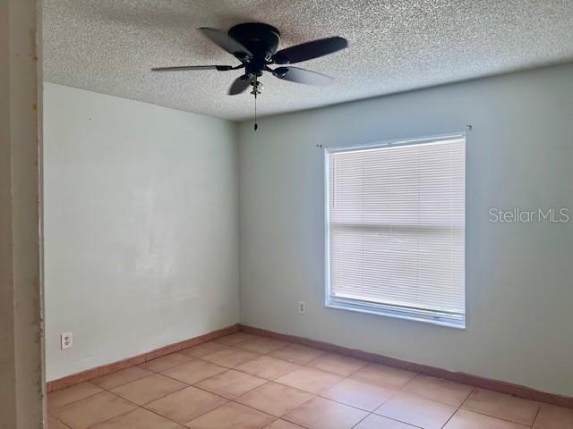 19 W Country Cove Way, Kissimmee, FL 34743 - unfurnished room with ceiling fan, a textured ceiling, light tile patterned flooring, and plenty of natural light