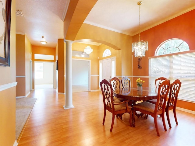 7985 Saint Giles Pl, Orlando, FL 32835 - dining area featuring decorative columns, light wood-style flooring, a chandelier, arched walkways, and crown molding