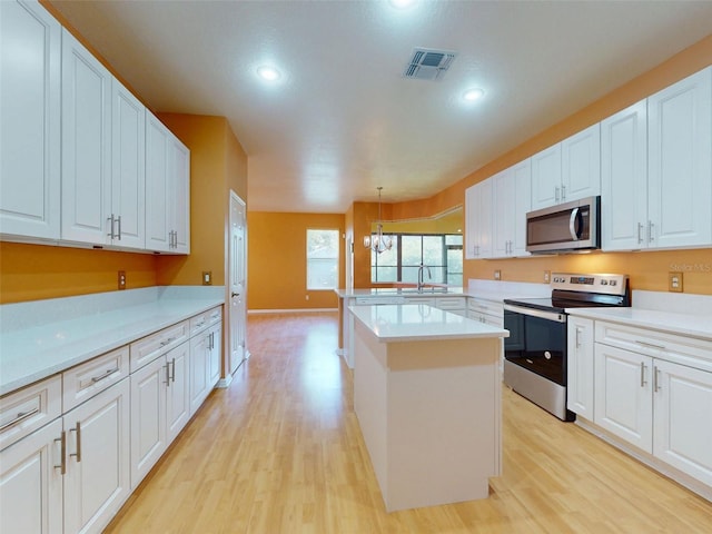 7985 Saint Giles Pl, Orlando, FL 32835 - kitchen featuring stainless steel appliances, light wood finished floors, light countertops, recessed lighting, and white cabinets