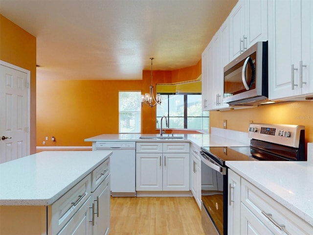 7985 Saint Giles Pl, Orlando, FL 32835 - kitchen with appliances with stainless steel finishes, a chandelier, light wood-style floors, a peninsula, and white cabinetry