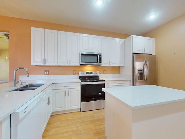 7985 Saint Giles Pl, Orlando, FL 32835 - kitchen with stainless steel appliances, light wood finished floors, light stone counters, white cabinets, and recessed lighting