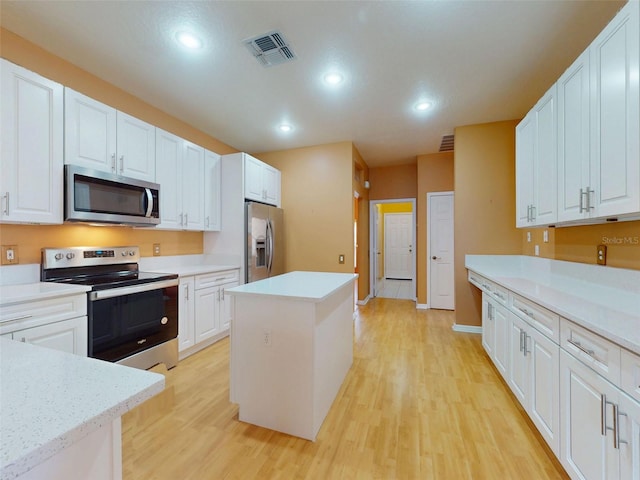7985 Saint Giles Pl, Orlando, FL 32835 - kitchen featuring appliances with stainless steel finishes, light wood-type flooring, a center island, white cabinetry, and recessed lighting