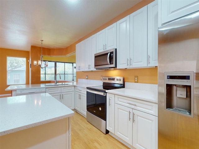 7985 Saint Giles Pl, Orlando, FL 32835 - kitchen featuring appliances with stainless steel finishes, a peninsula, white cabinetry, light wood-style flooring, and a chandelier