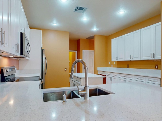 7985 Saint Giles Pl, Orlando, FL 32835 - kitchen featuring range with electric cooktop, recessed lighting, freestanding refrigerator, white cabinets, and light stone counters