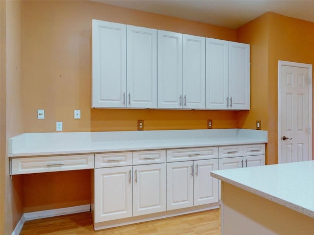 7985 Saint Giles Pl, Orlando, FL 32835 - kitchen with light wood-style flooring, light countertops, white cabinetry, and a desk