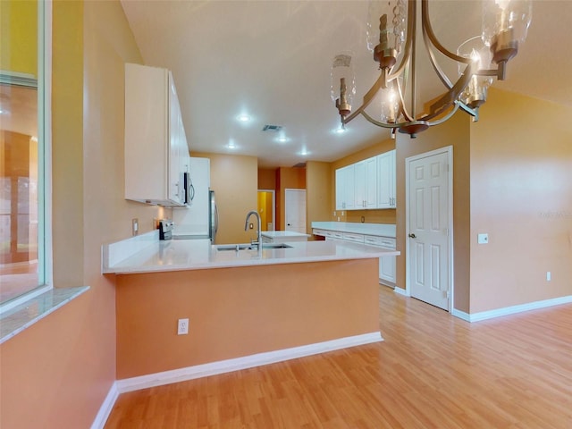 7985 Saint Giles Pl, Orlando, FL 32835 - kitchen with a chandelier, a peninsula, light wood-type flooring, and light countertops