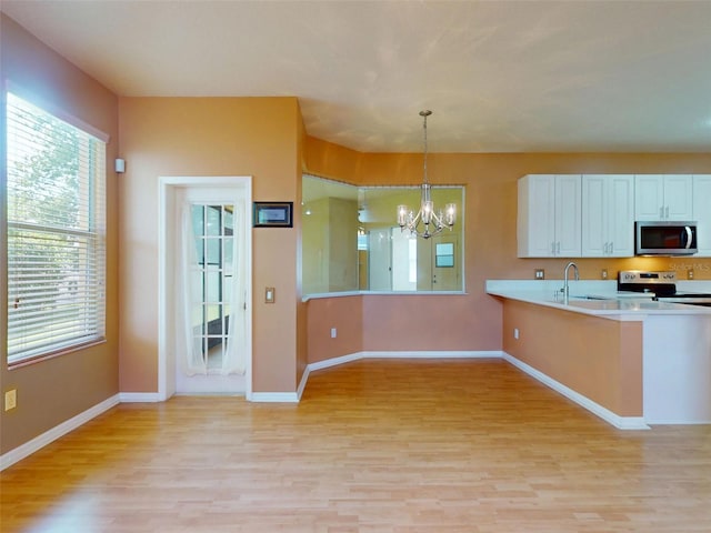 7985 Saint Giles Pl, Orlando, FL 32835 - kitchen with appliances with stainless steel finishes, a chandelier, light wood-style flooring, and light countertops
