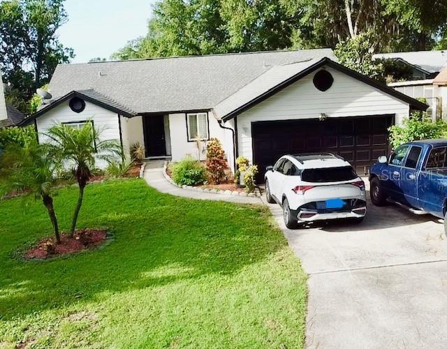 957 Southridge Trl, Altamonte Springs, FL 32714 - ranch-style home with concrete driveway, a front lawn, an attached garage, and a shingled roof