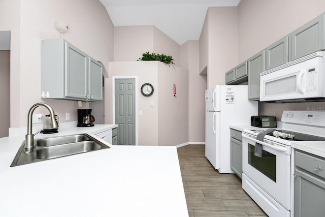 1520 Gulf Vue Dr, Haines City, FL 33844 - kitchen featuring white appliances, light countertops, light wood-type flooring, gray cabinetry, and vaulted ceiling