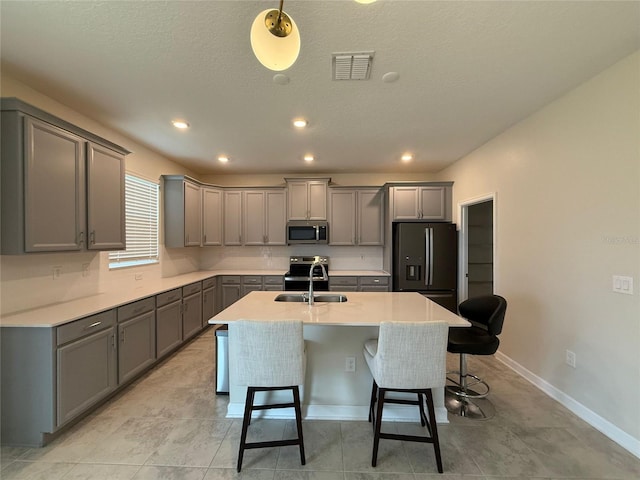 18219 Oliver Twist Way, Winter Garden, FL 34787 - kitchen featuring stainless steel appliances, gray cabinetry, a kitchen breakfast bar, an island with sink, and a textured ceiling