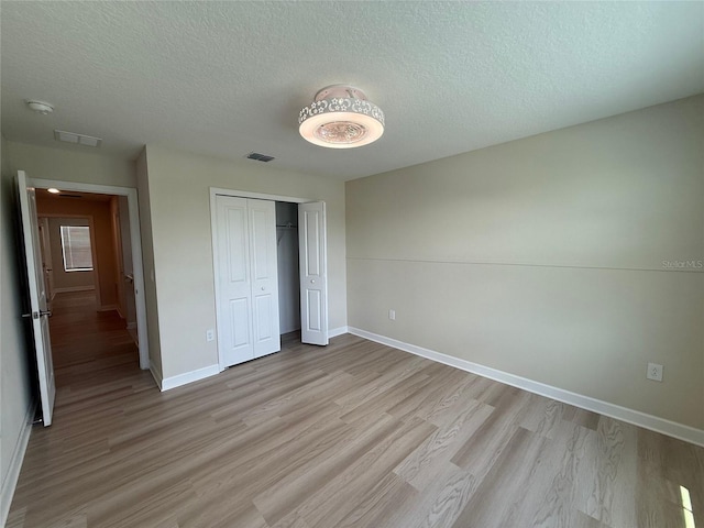 18219 Oliver Twist Way, Winter Garden, FL 34787 - unfurnished bedroom with light wood-style flooring, a textured ceiling, and a closet