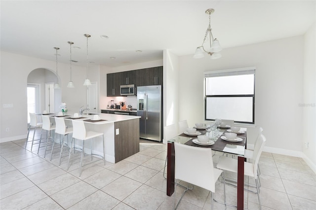 207 Macaulays Cv, Haines City, FL 33844 - kitchen with appliances with stainless steel finishes, light tile patterned floors, arched walkways, a center island with sink, and a kitchen bar