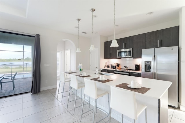 207 Macaulays Cv, Haines City, FL 33844 - kitchen with stainless steel appliances, arched walkways, backsplash, a kitchen bar, and a center island with sink