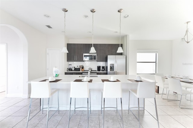 207 Macaulays Cv, Haines City, FL 33844 - kitchen with fridge with ice dispenser, stainless steel microwave, backsplash, light countertops, and a center island with sink
