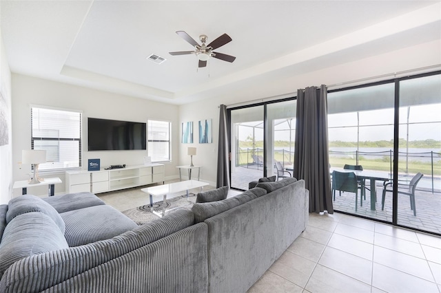 207 Macaulays Cv, Haines City, FL 33844 - living area with ceiling fan, a raised ceiling, light tile patterned floors, and plenty of natural light