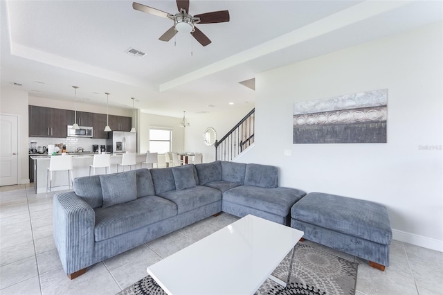 207 Macaulays Cv, Haines City, FL 33844 - living room with ceiling fan, stairway, a tray ceiling, and light tile patterned floors