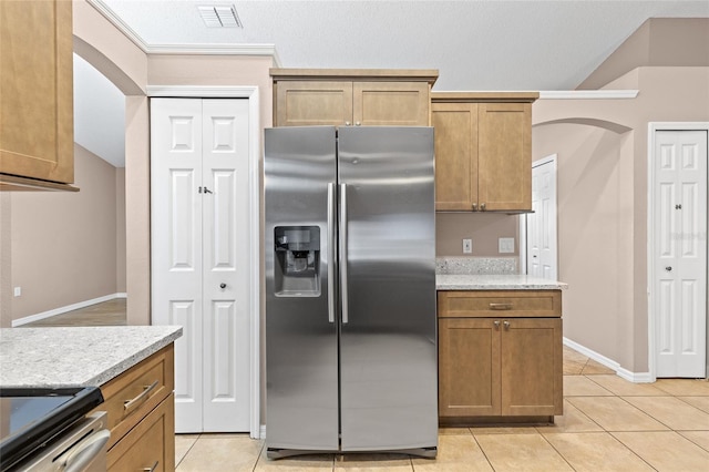 3245 Kings Ridge Ter, Deltona, FL 32725 - kitchen featuring appliances with stainless steel finishes, light tile patterned floors, brown cabinetry, vaulted ceiling, and arched walkways