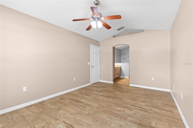 3245 Kings Ridge Ter, Deltona, FL 32725 - spare room featuring arched walkways, a ceiling fan, vaulted ceiling, light wood finished floors, and a textured ceiling