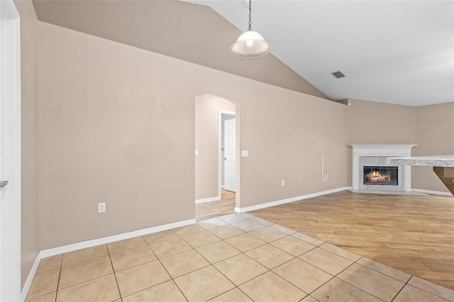 3245 Kings Ridge Ter, Deltona, FL 32725 - unfurnished living room featuring vaulted ceiling, arched walkways, a high end fireplace, and light wood finished floors