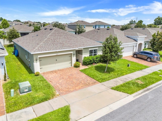 9370 Westmorely St, Groveland, FL 34736 - view of front of home with roof with shingles, an attached garage, stucco siding, and a front lawn