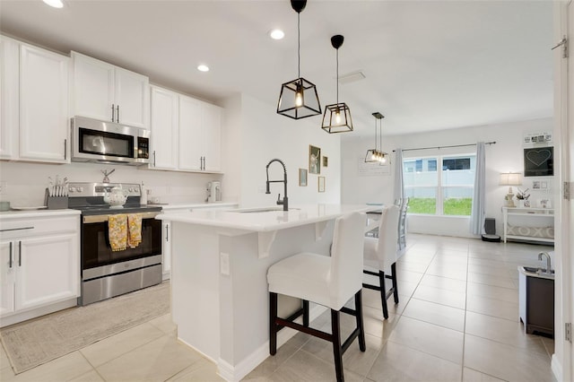 9370 Westmorely St, Groveland, FL 34736 - kitchen with appliances with stainless steel finishes, light countertops, white cabinets, recessed lighting, and a kitchen bar
