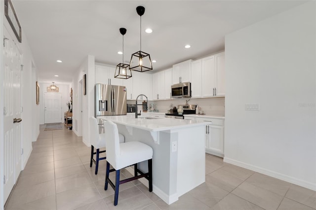 9370 Westmorely St, Groveland, FL 34736 - kitchen featuring appliances with stainless steel finishes, a breakfast bar, light countertops, an island with sink, and white cabinetry