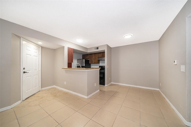 5140 Conroy Rd Unit 16, Orlando, FL 32811 - kitchen featuring light tile patterned flooring, freestanding refrigerator, a peninsula, stove, and recessed lighting