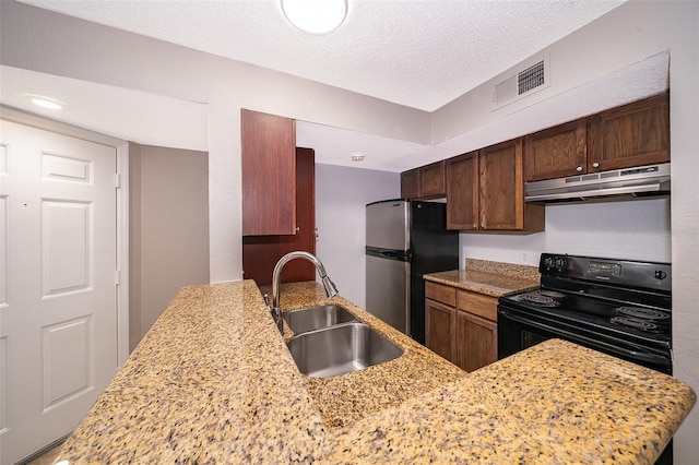 5140 Conroy Rd Unit 16, Orlando, FL 32811 - kitchen with electric range, under cabinet range hood, freestanding refrigerator, light stone counters, and a textured ceiling