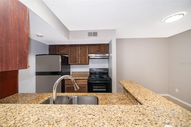 5140 Conroy Rd Unit 16, Orlando, FL 32811 - kitchen with black range with electric cooktop, freestanding refrigerator, light stone countertops, under cabinet range hood, and a textured ceiling