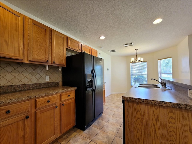 1914 Commander Way, Kissimmee, FL 34746 - kitchen with black fridge, a chandelier, decorative backsplash, light tile patterned flooring, and brown cabinetry