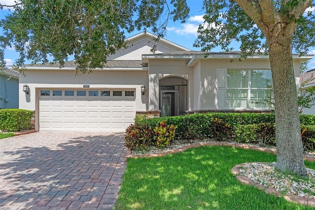3685 Corsica Ln, Clermont, FL 34711 - view of front of house featuring stucco siding, decorative driveway, an attached garage, and a front lawn