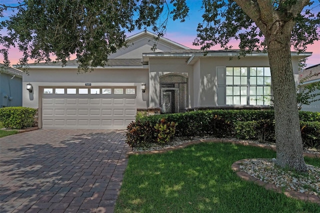 3685 Corsica Ln, Clermont, FL 34711 - view of front of house featuring stucco siding, an attached garage, decorative driveway, and a front lawn