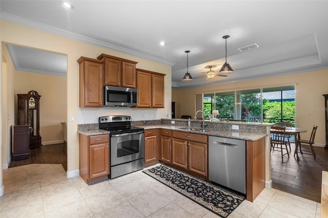 3685 Corsica Ln, Clermont, FL 34711 - kitchen featuring appliances with stainless steel finishes, brown cabinetry, a peninsula, crown molding, and light stone counters