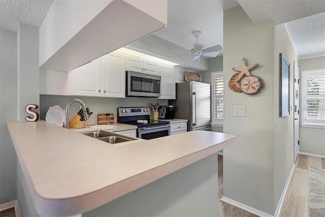 431 Cerromar Ln Unit 446, Venice, FL 34293 - kitchen featuring appliances with stainless steel finishes, a textured ceiling, light countertops, a peninsula, and white cabinetry
