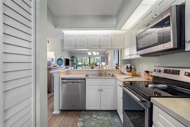 431 Cerromar Ln Unit 446, Venice, FL 34293 - kitchen featuring stainless steel appliances, white cabinetry, light countertops, wood finished floors, and a peninsula