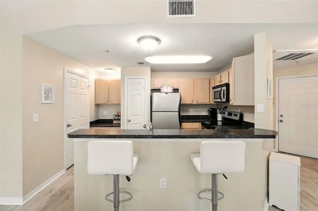 2025 Erving Cir Unit 203, Ocoee, FL 34761 - kitchen featuring stainless steel appliances, a peninsula, a breakfast bar, light wood-style floors, and light brown cabinetry