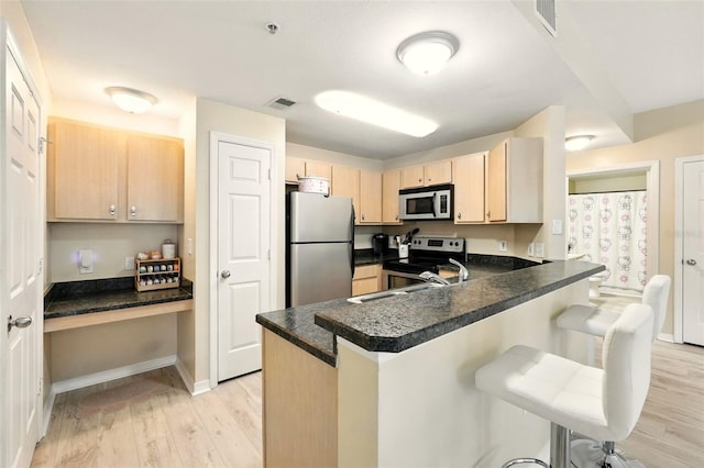 2025 Erving Cir Unit 203, Ocoee, FL 34761 - kitchen featuring stainless steel appliances, light brown cabinetry, a peninsula, light wood-type flooring, and a breakfast bar area
