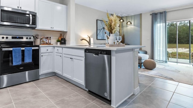 2424 Penguin Blvd, Davenport, FL 33837 - kitchen featuring stainless steel appliances, a peninsula, light tile patterned floors, white cabinetry, and light countertops